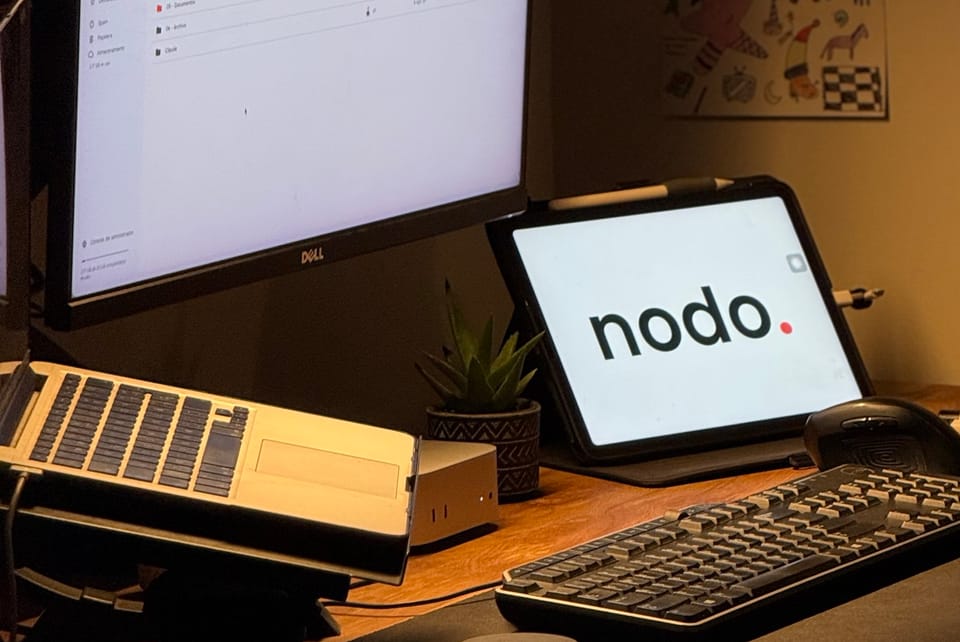 El escritorio de trabajo de nodo: un monitor, un teclado y un iPad con el logo de nodo.
